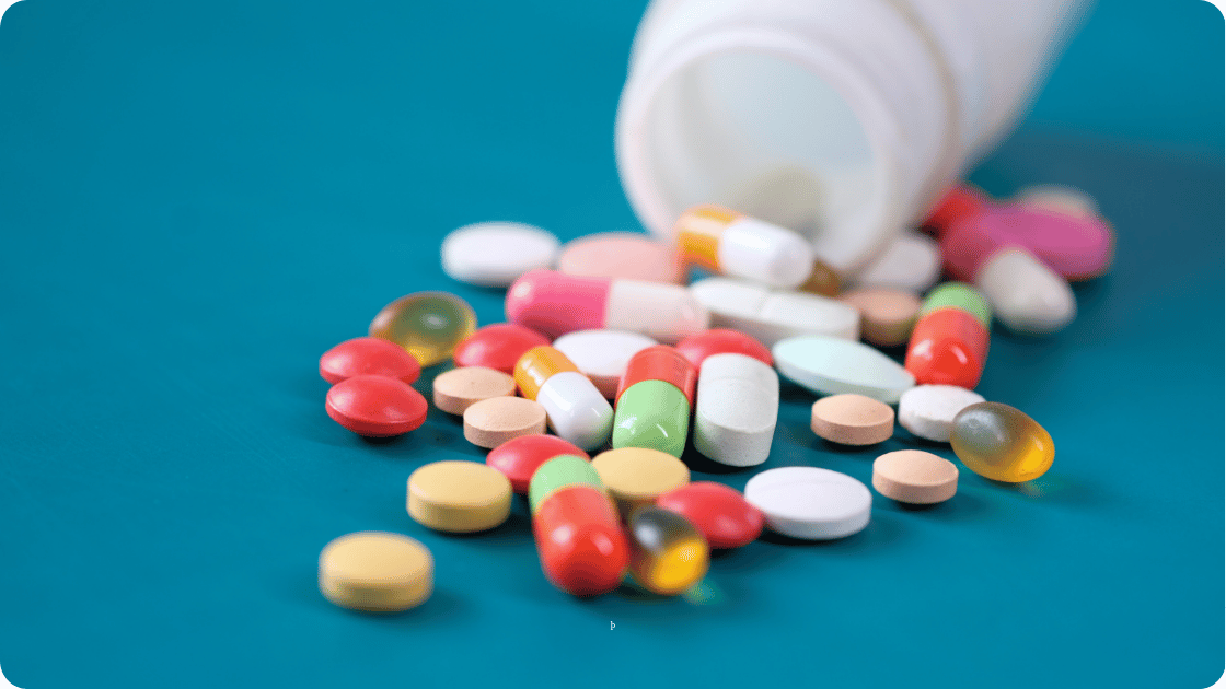 Bottle on blue background with pills in front of it